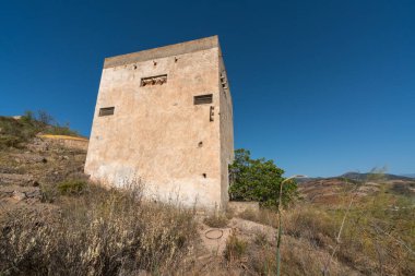 Güney İspanya 'da terk edilmiş bir maden tesisinde inşaat taş, tuğla ve betondan yapılmıştır. Ağaçlar ve çalılar vardır. Gökyüzü açıktır.