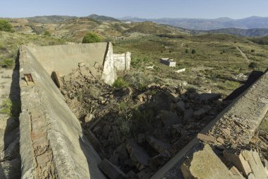 Güney İspanya 'da terk edilmiş bir maden tesisinde inşaat taş, tuğla ve betondan yapılmıştır. Ağaçlar ve çalılar vardır. Gökyüzü açıktır.