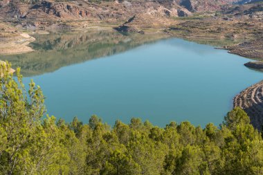 Güney İspanya 'da Beninar Barajı Suda yansımalar, çam ağaçları ve çalılar var
