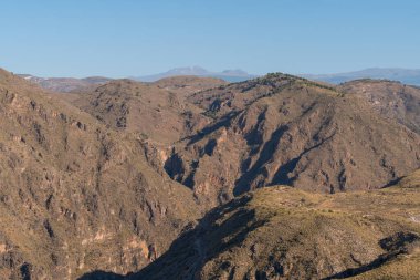 Güney İspanya 'nın dağlık arazisi, çalılar ve ağaçlar var, gökyüzü açık.