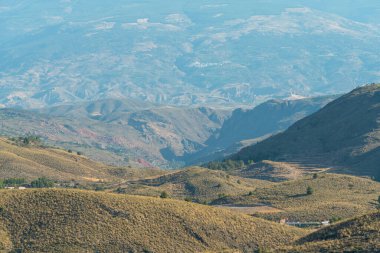 İspanya 'nın güneyindeki dağlık bölgede birkaç çiftlik evi, çalılar ve ağaçlar var.