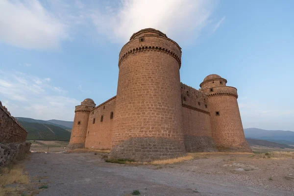 Güney İspanya 'daki bir dağın tepesinde La Calahorra kalesi. Kale taştan yapılmış, 3 kulesi var, çimenler kuru.