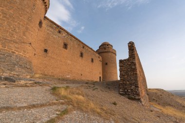 Güney İspanya 'da bir kalenin taş duvarı, duvarın birkaç penceresi var, kuru bitki örtüsü var, gökyüzü temiz.