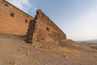 Güney İspanya 'da bir kalenin taş duvarı, duvarın birkaç penceresi var, kuru bitki örtüsü var, gökyüzü temiz.