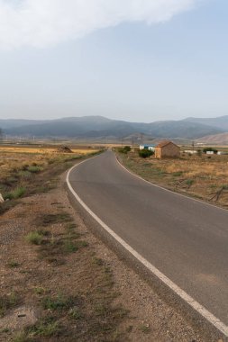Güney İspanya 'da La Calahorra' da asfalt yol var, binalar var, bitkiler ve dağlar var, gökyüzünde bulutlar var.