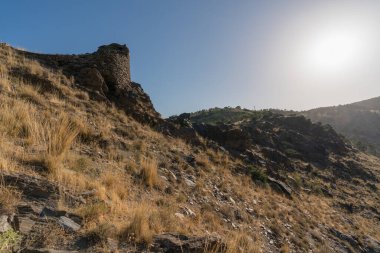 İspanya 'nın güneyinde Sierra Nevada, dağlık bir bölge, çalılar ve çimenler kuru, taştan yapılmış eski bir duvar var, gökyüzü temiz.