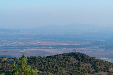 Sierra Nevada 'da bir dağın tepesindeki korucu evinde ağaçlar ve kayalar var. Binaların olduğu bir ova var.