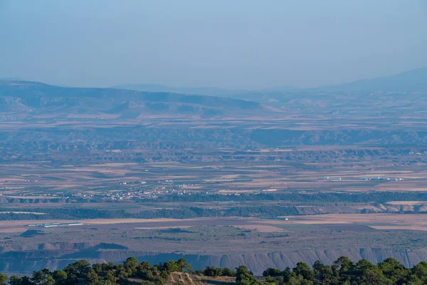 İspanya 'nın güneyinde çorak topraklar, bir kasaba, ağaçlar ve dağlar var, gökyüzü açık.