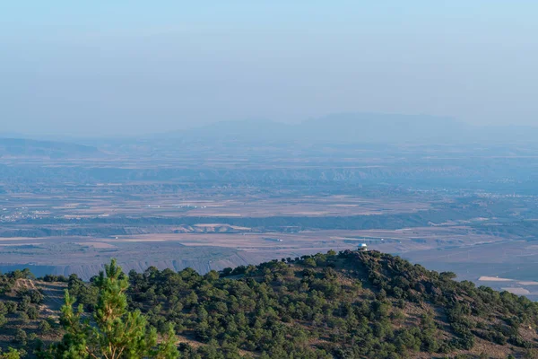 Sierra Nevada 'da bir dağın tepesindeki korucu evinde ağaçlar ve kayalar var. Binaların olduğu bir ova var.