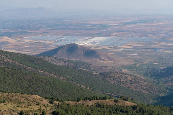 Sierra Nevada dağlarının yamaçlarında, dağlarda çam ormanı, bir güneş enerjisi santrali ve düz bir alan var, birkaç köy var.