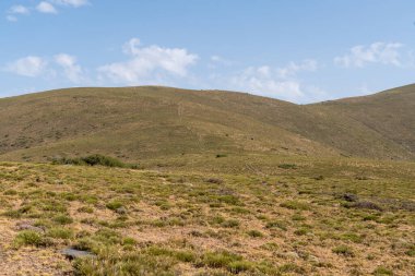 Güney İspanya 'da Sierra Nevada' nın dağlık arazisi, çalılar ve çimenler var, taşlar var ve gökyüzünde bulutlar var.