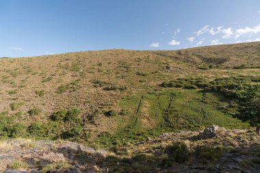 Güney İspanya 'da Sierra Nevada' nın dağlık arazisi, çalılar ve çimenler, taşlar ve kayalar var, gökyüzünde bulut var.