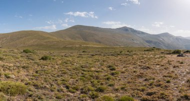 Güney İspanya 'da Sierra Nevada' nın dağlık arazisi, çalılar ve çimenler var, taşlar var ve gökyüzünde bulutlar var.