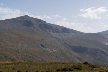 Güney İspanya 'da Sierra Nevada' nın dağlık arazisi, çalılar ve çimenler var, taşlar var ve gökyüzünde bulutlar var.