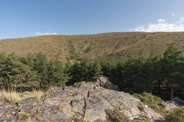 Güney İspanya 'da Sierra Nevada' nın dağlık arazisi, çalılar ve çimenler, taşlar ve kayalar var, gökyüzünde bulut var.