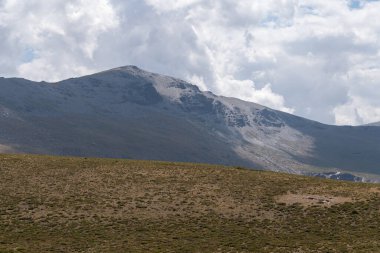Güney İspanya 'da Sierra Nevada' nın dağlık arazisi, çalılar ve çimenler var, taşlar ve kayalar var, gökyüzünde bulutlar var.