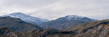 Güney İspanya 'nın dağlık arazisi, dağ karlı, bitki örtüsü var ve gökyüzü bulutlu.