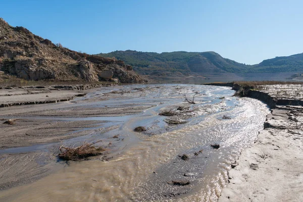 Güney İspanya 'daki Beninar rezervuarına doğru akan su nehri, dağlar ve ağaçlar var, taşlar var ve gökyüzü açık.