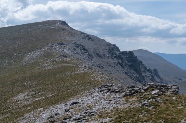 Sierra Nevada 'daki dağlık arazi, çalılar ve çimenler, taşlar ve kayalar var, gökyüzü bulutlu.