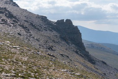 Sierra Nevada dağında kaya oluşumu, yüksek dağ çalıları, gökyüzü bulutlu.