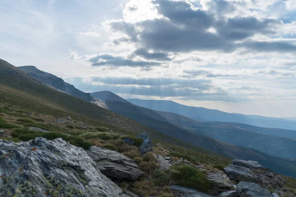 Sierra Nevada 'daki dağlık arazi, çalılar ve çimenler, taşlar ve kayalar var, gökyüzü bulutlu.