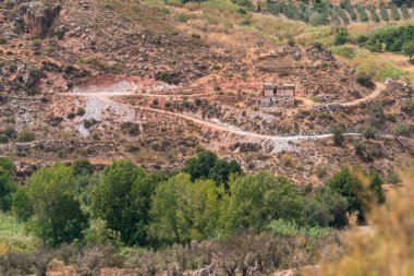 Güney İspanya 'daki eski çiftlik evi, çalılar ve ağaçlar var, kayalar var, gökyüzü bulutlu.