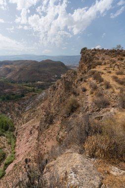 Güney İspanya 'da La Alpujarra' nın dağlık arazisi, ağaçlar ve çalılar var, taşlar ve kayalar var, gökyüzünde bulutlar var.