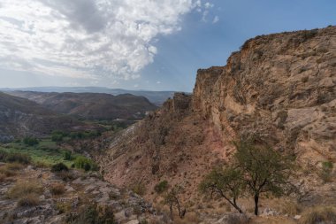 Güney İspanya 'da La Alpujarra' nın dağlık arazisi, ağaçlar ve çalılar var, taşlar ve kayalar var, gökyüzünde bulutlar var.