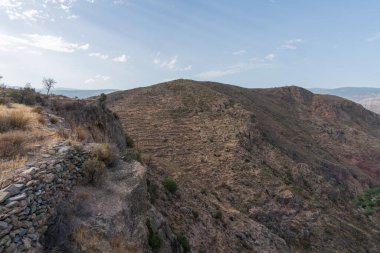 Güney İspanya 'da La Alpujarra' nın dağlık arazisi, ağaçlar ve çalılar var, taşlar ve kayalar var, gökyüzünde bulutlar var.