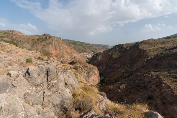 Güney İspanya 'da La Alpujarra' nın dağlık arazisi, ağaçlar ve çalılar var, taşlar ve kayalar var, gökyüzünde bulutlar var.