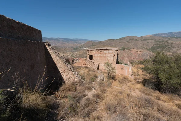 İspanya 'nın güneyindeki bir dağda harabe ve terk edilmiş bir çiftlik evi, çiftlik evinin pencere ve kapıları, çalılar ve ağaçlar var, gökyüzü açık.