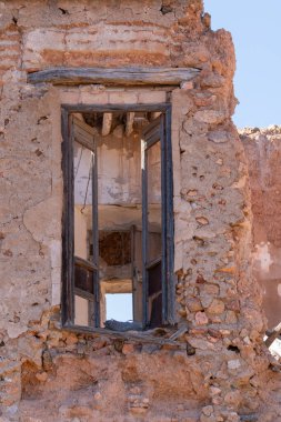 Eski bir çiftliğin eski kapısı, kapı ahşaptan yapılmıştır, duvar taş ve çamurdan yapılmıştır, kapının üstünde ahşap bir kiriş vardır.