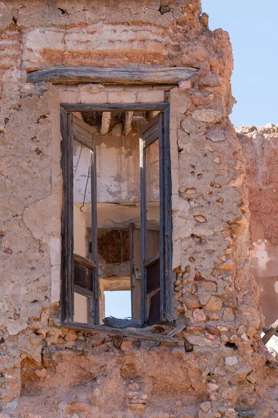 Eski bir çiftliğin eski kapısı, kapı ahşaptan yapılmıştır, duvar taş ve çamurdan yapılmıştır, kapının üstünde ahşap bir kiriş vardır.