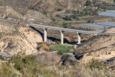 Güney İspanya 'da bir yol köprüsü, iki yol ve birkaç çiftlik evi, ağaçlar ve çalılar, birkaç sera var.