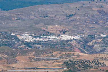 Sierra Nevada dağının yamacında bir köy. Evlerin beyaz cepheleri var. Ağaçlar ve vadi var.