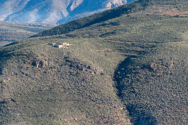 Güney İspanya 'da bir dağda yıkıntılar, çalılar ve ağaçlar var, bir vadinin yanında kayalar var.