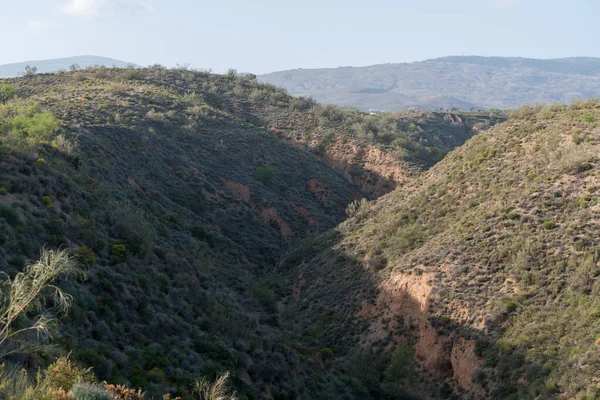 İspanya 'nın güneyindeki dağlık alanda ağaçlar ve çalılar var, bir vadi var, gökyüzü açık.