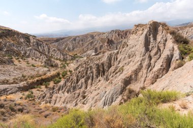 Güney İspanya 'da dağlık ve aşınmış bir arazi, bitki örtüsü var ve gökyüzü bulutlu.