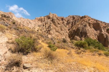 Güney İspanya 'da dağlık ve aşınmış bir arazi, bitki örtüsü var ve gökyüzü bulutlu.