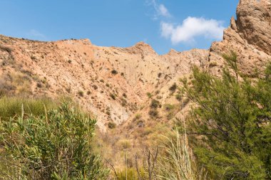 Güney İspanya 'da dağlık ve aşınmış bir arazi, bitki örtüsü var ve gökyüzü bulutlu.