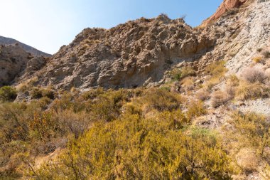 Güney İspanya 'da dağlık ve aşınmış bir arazi, bitki örtüsü var ve gökyüzü bulutlu.