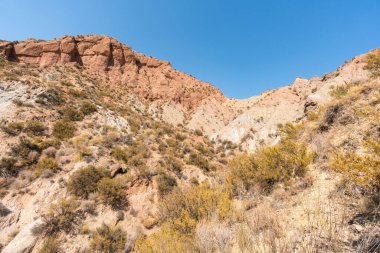 Güney İspanya 'da dağlık ve aşınmış bir arazi, bitki örtüsü var ve gökyüzü bulutlu.