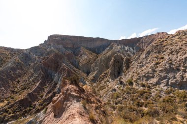 Güney İspanya 'da dağlık ve aşınmış bir arazi, bitki örtüsü var ve gökyüzü bulutlu.