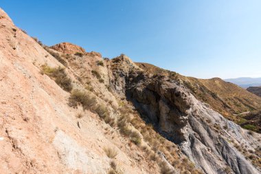 Güney İspanya 'da dağlık ve aşınmış bir arazi, bitki örtüsü var ve gökyüzü bulutlu.