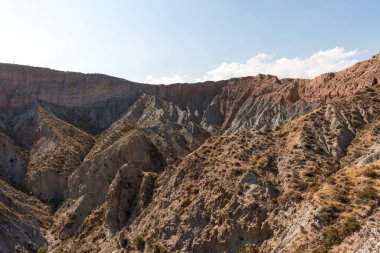 Güney İspanya 'da dağlık ve aşınmış bir arazi, bitki örtüsü var ve gökyüzü bulutlu.