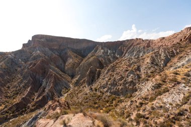 Güney İspanya 'da dağlık ve aşınmış bir arazi, bitki örtüsü var ve gökyüzü bulutlu.