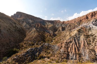 Güney İspanya 'da dağlık ve aşınmış bir arazi, bitki örtüsü var ve gökyüzü bulutlu.