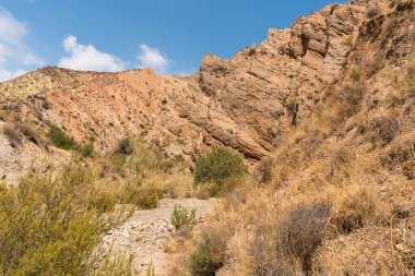 Güney İspanya 'da dağlık ve aşınmış bir arazi. Kuru bir vadi var, bitki örtüsü var ve gökyüzü bulutlu.