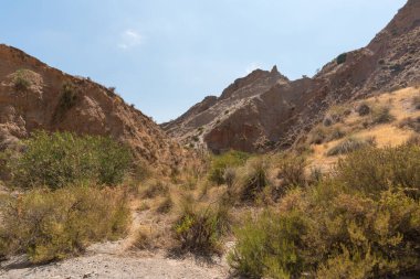 Güney İspanya 'da dağlık ve aşınmış bir arazi. Kuru bir vadi var, bitki örtüsü var ve gökyüzü açık.