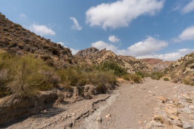 Güney İspanya 'da dağlık ve aşınmış bir arazi. Kuru bir vadi var, bitki örtüsü var ve gökyüzü bulutlu.